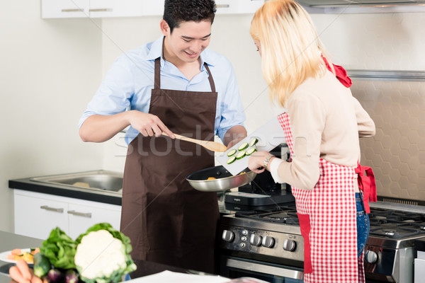 Asian couple cooking vegetables in frying pan Stock photo © Kzenon