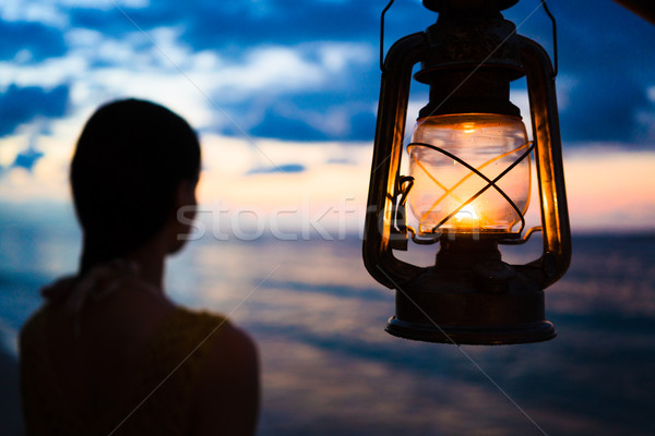 Woman in lantern shine looking to sea at sunset  Stock photo © Kzenon