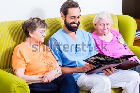 Geriatric nurse looking at pictures with seniors Stock photo © Kzenon