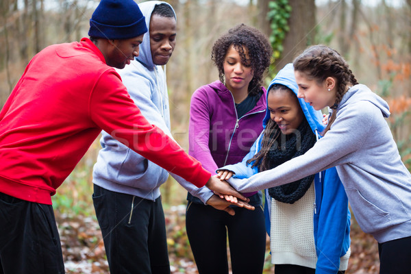 Five young people holding hands together before workout Stock photo © Kzenon