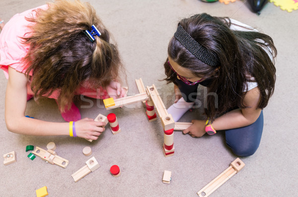 High-angle view of two pre-school girls sharing wooden toy blocks Stock photo © Kzenon