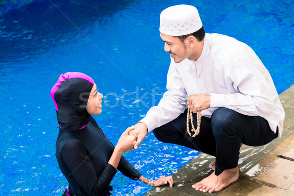 Stock photo: Muslim woman in pool greeting her husband