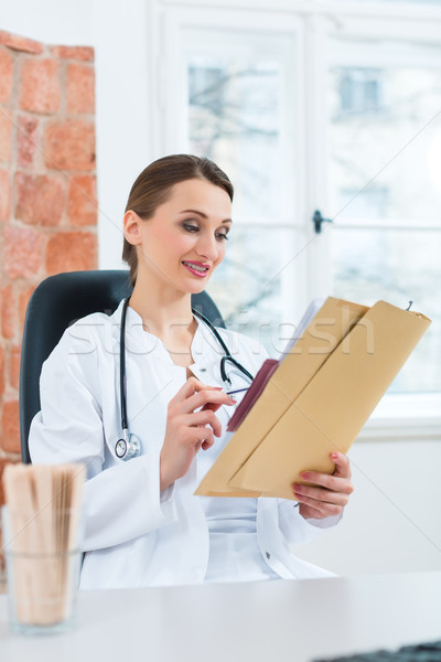 Female doctor reading in document Stock photo © Kzenon