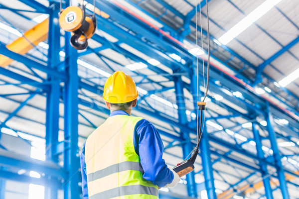 Worker in factory controlling crane with remote Stock photo © Kzenon