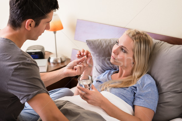 Young caring man giving pill to his sick partner Stock photo © Kzenon