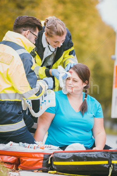 Emergency medics dressing head wound of injured woman Stock photo © Kzenon