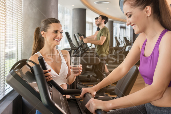 Young woman helping her friend to set the parameters of treadmill Stock photo © Kzenon