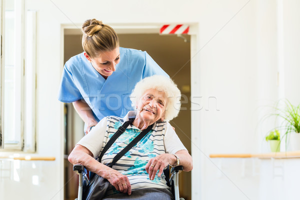 Caregiver with senior patient in wheel chair Stock photo © Kzenon