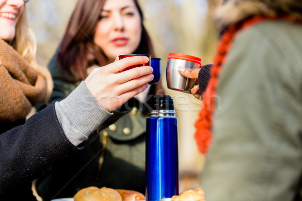 Young female friends drinking a hot beverage outdoors in winter Stock photo © Kzenon