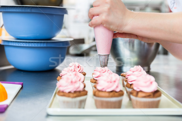Women in pastry bakery as confectioner glazing muffins with icing Stock photo © Kzenon