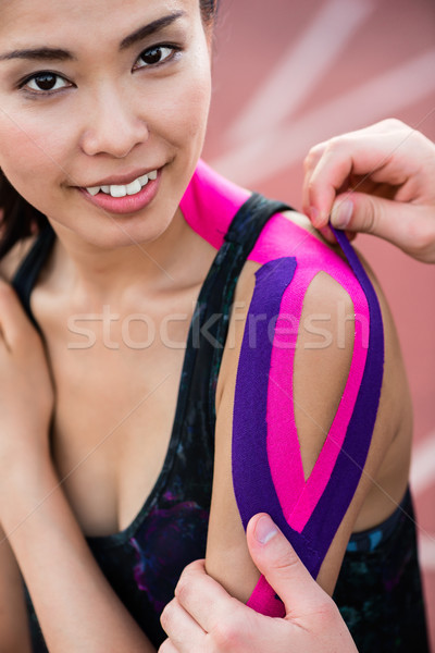 Woman taping with therapeutic tape on cinder track of stadium Stock photo © Kzenon