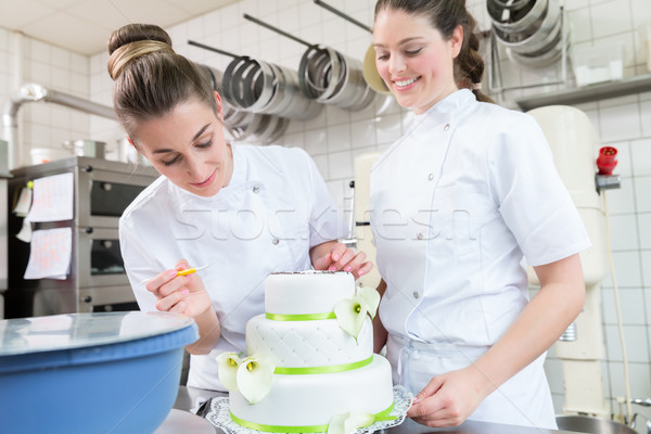 Two pastry bakers decorating large cake Stock photo © Kzenon