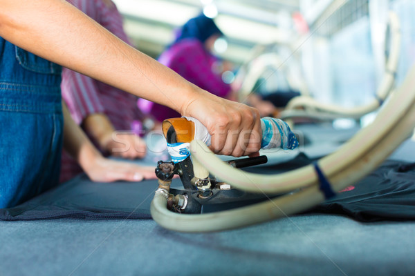 Indonesian worker with flat iron in textile factory Stock photo © Kzenon