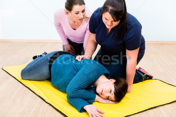 Women in first aid class training to position injured person Stock photo © Kzenon