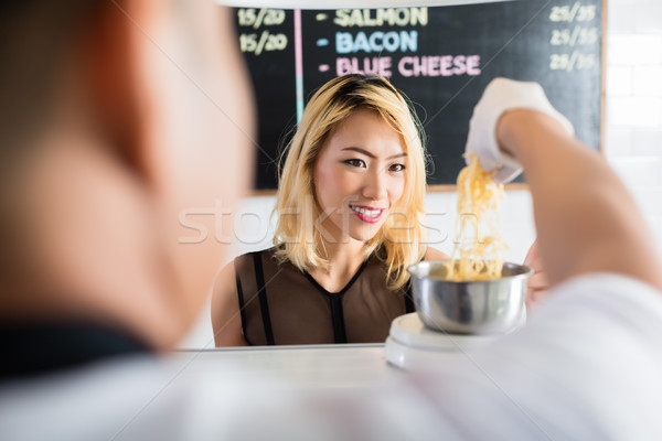 Asian woman watching as cheese is put on a scale Stock photo © Kzenon