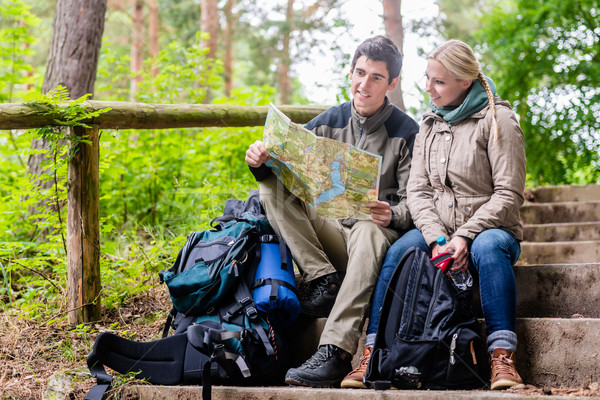 Man and woman on hike planning next route section on map Stock photo © Kzenon