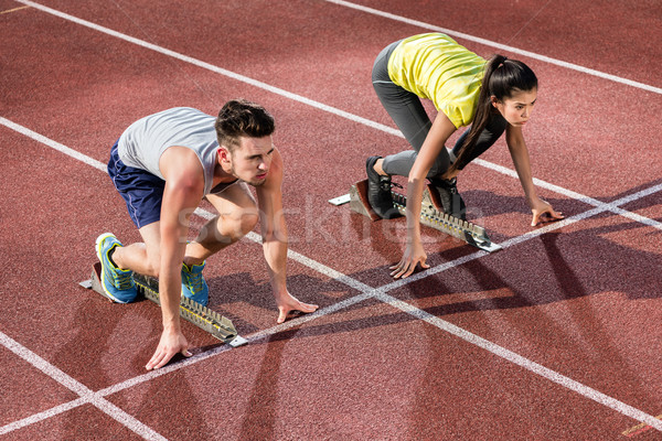 Male and female athlete in starting position at starting block o Stock photo © Kzenon