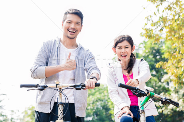Young Asian couple laughing together while riding bicycles  Stock photo © Kzenon
