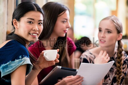 Three young women looking at pictures on tablet Stock photo © Kzenon