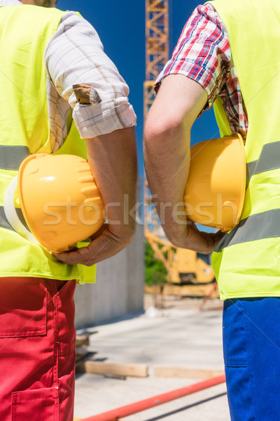 Rear view of the hands of two workers holding yellow hard hats Stock photo © Kzenon
