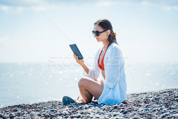 Woman reading a novel on ebook by the sea Stock photo © Kzenon