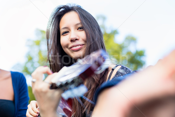 Guitar player girl making music with friends in park Stock photo © Kzenon