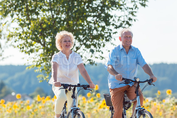 Active elderly couple riding bicycles together in the countrysid Stock photo © Kzenon