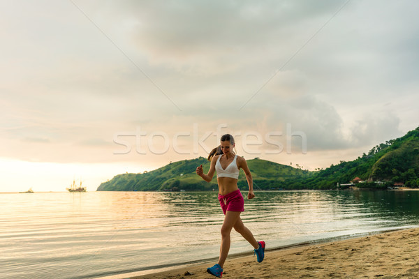 Fit young woman running on the beach during summer vacation Stock photo © Kzenon