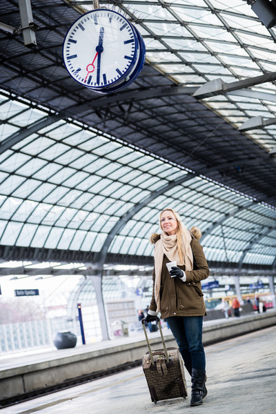 Stock photo: Woman looking at clock in train station as her train has a delay