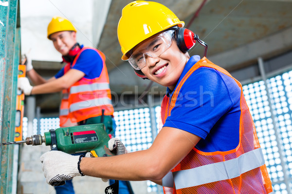 Asian construction workers drilling in building walls Stock photo © Kzenon