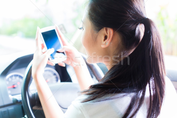 Asian woman texting while driving car Stock photo © Kzenon