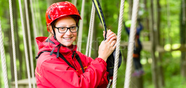 Girl roping up in high rope course Stock photo © Kzenon
