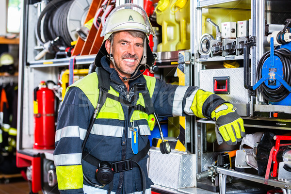 Fire fighter in protective clothes leaning at fire engine Stock photo © Kzenon