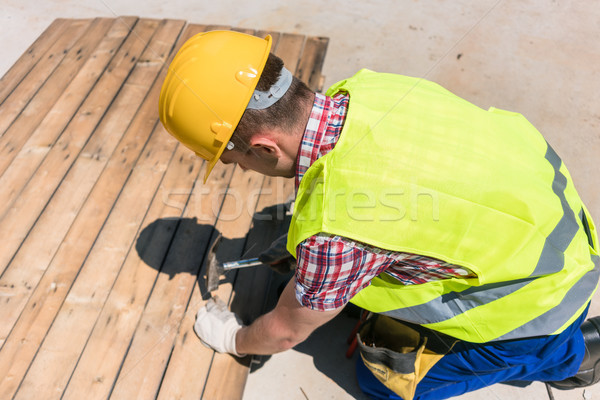 High-angle view of a blue-collar worker using a hammer on the co Stock photo © Kzenon