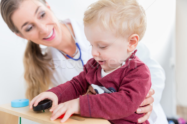 Cute active baby boy playing with toys during physical examination Stock photo © Kzenon