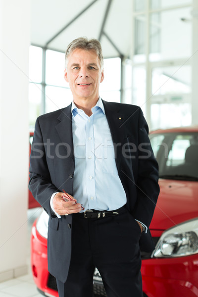 Mature man with auto in car dealership Stock photo © Kzenon