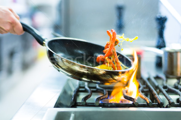 Chef in restaurant kitchen at stove with pan Stock photo © Kzenon