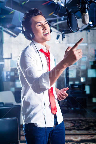 Asian male singer producing song in recording studio Stock photo © Kzenon