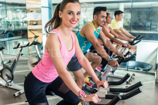 Beautiful fit woman smiling during cardio workout at indoor cycl Stock photo © Kzenon
