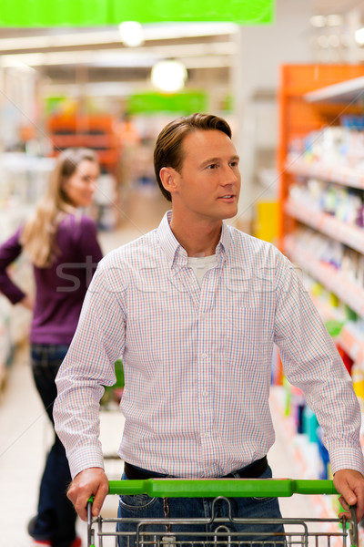 Stock photo: Man and woman in supermarket with shopping cart