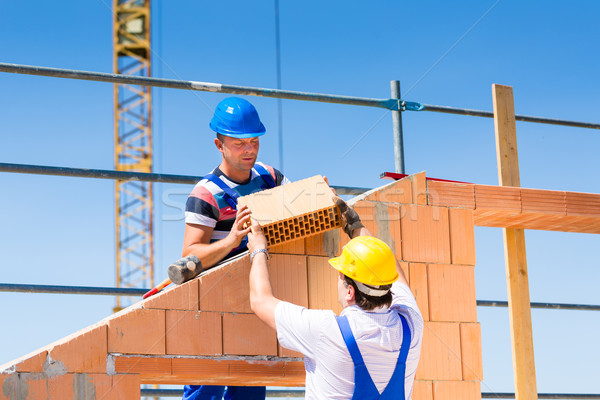 Bricklayer or builders on construction site working Stock photo © Kzenon