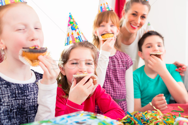 Children at birthday party with muffins and cake Stock photo © Kzenon
