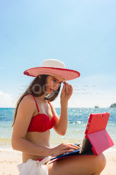 Successful female entrepreneur managing her business online while on the beach Stock photo © Kzenon