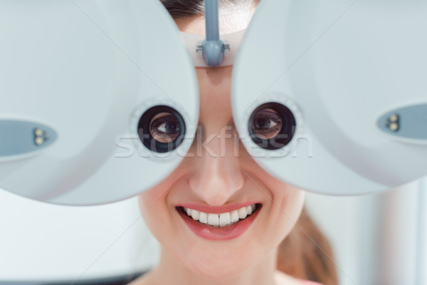 Woman having her eyesight measured with phoropter Stock photo © Kzenon