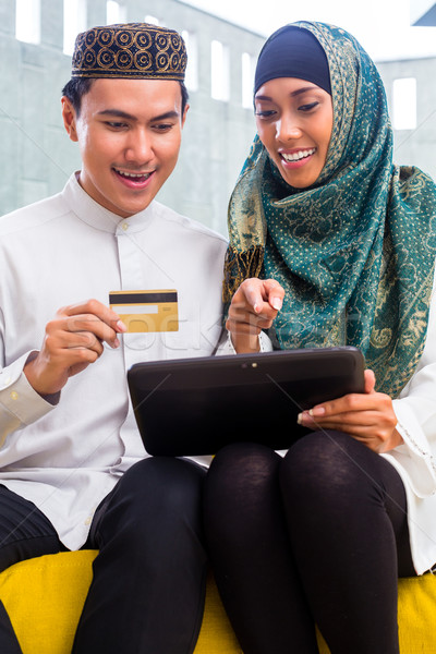Asian Muslim couple shopping online on pad in living room Stock photo © Kzenon