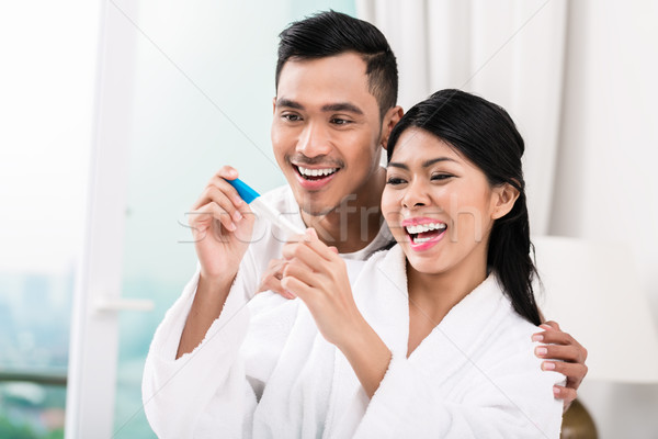 Stock photo: Asian couple with pregnancy test in bed