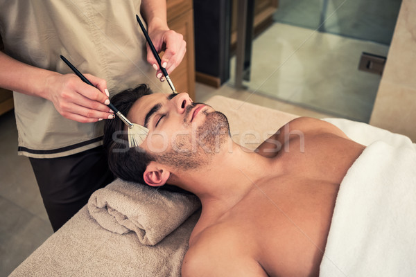 Stock photo: Man lying down during traditional facial treatment at beauty cen