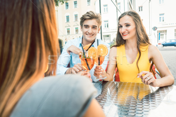 Happy couple toasting with their mutual female friend at a trendy restaurant Stock photo © Kzenon