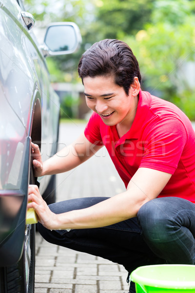 Asian man cleaning car rims with sponge Stock photo © Kzenon