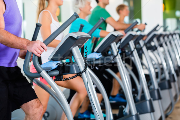 Group with senior people on elliptical trainer in gym Stock photo © Kzenon